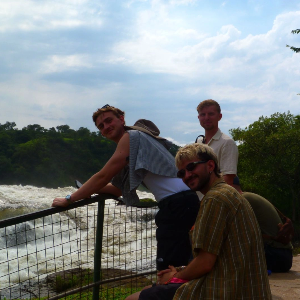 Visitors leaning on a railing above a rapid river with forest behind