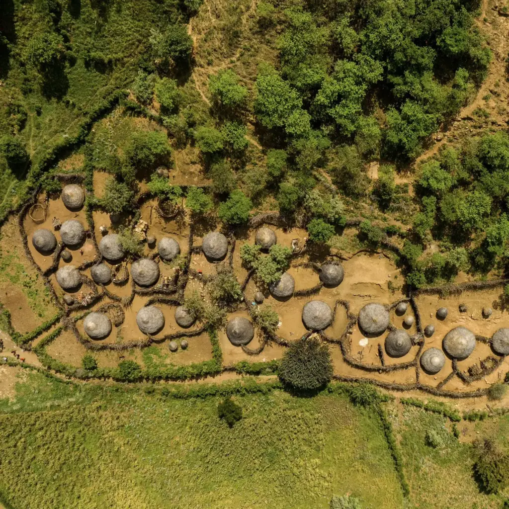 Aerial view of a hillside Karamojong homestead above green farmland, Uganda