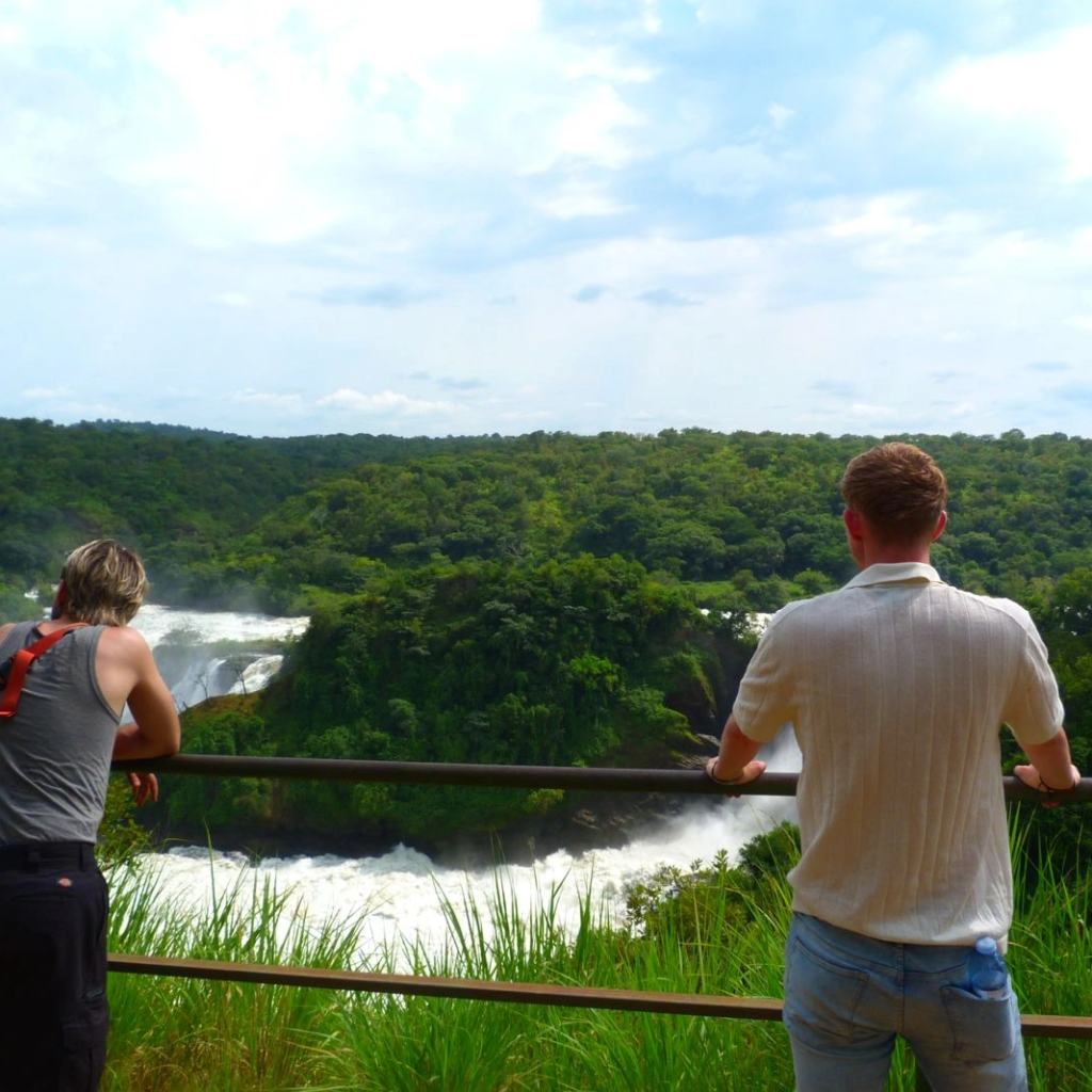 A man looking out at a waterfall cascading through forest