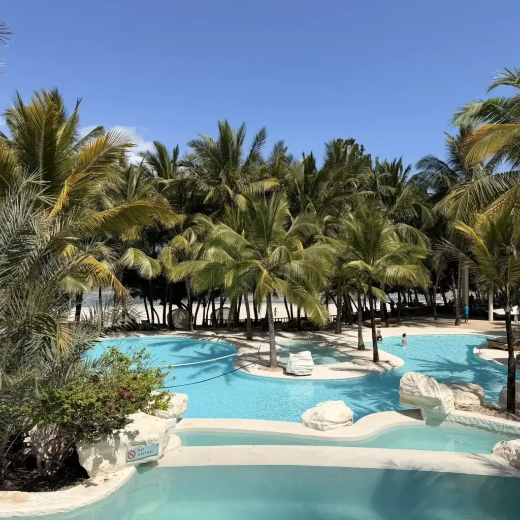 A turquoise resort pool among palm trees on the Zanzibar coast